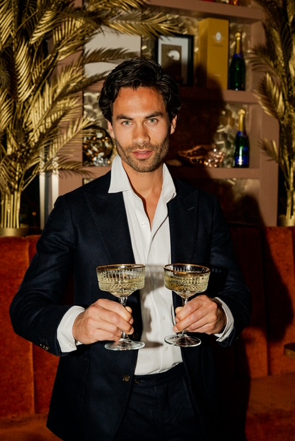 Gastheer met twee vergulde champagnecoupes in het sfeervolle interieur van Bar Santé
